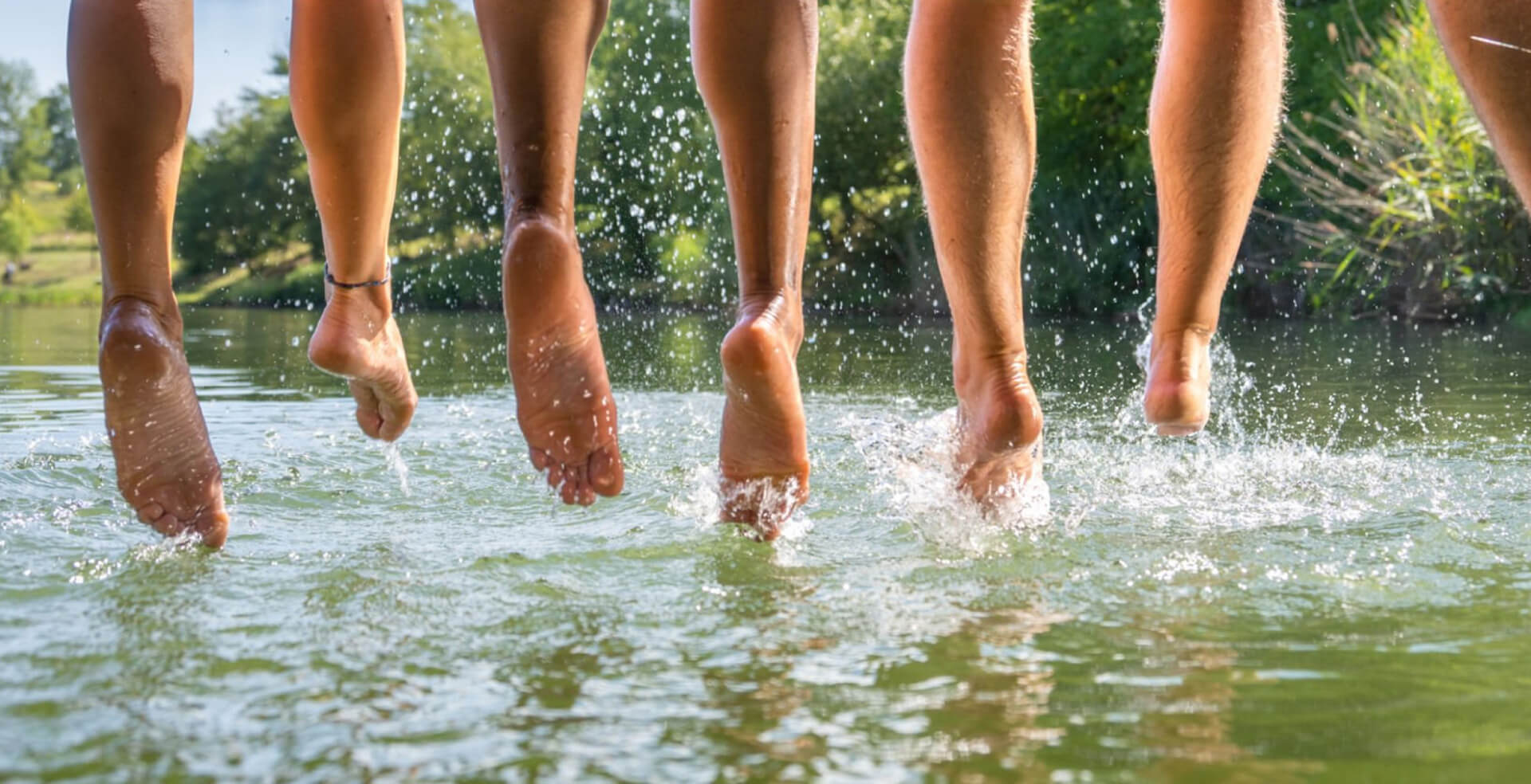 Friends jumping into a pond